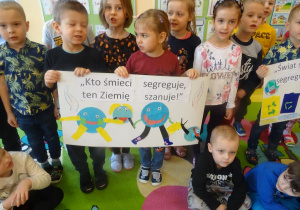 Grupa dzieci stoi z plakatem ekologicznym.